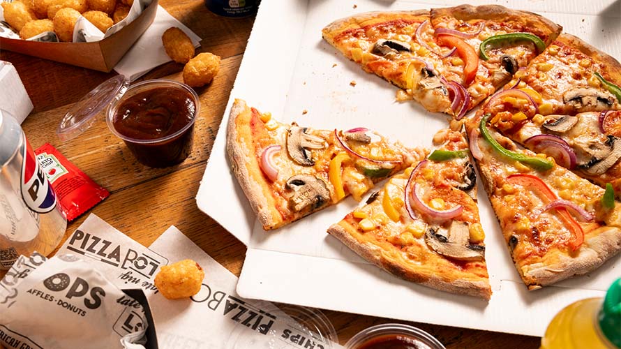 A takeaway pizza surrounded by dips and snacks