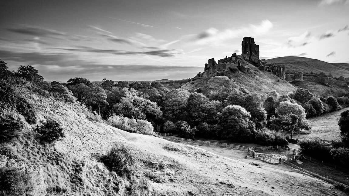 Corfe Castle set amongst rolling hills and trees