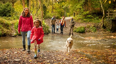 A family on an autumnal woodland walk with their dog
