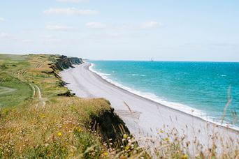 A view from the grassy cliffs lining a stretch of beach on the Norfolk coast