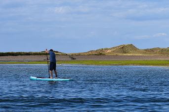 A paddleboarder on the calm waters of the Norfolk Broads