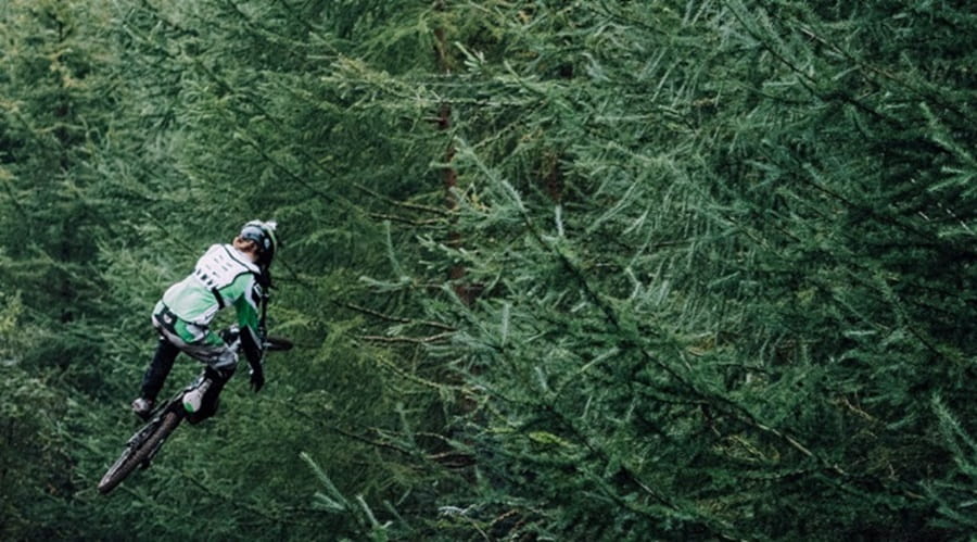 A man extreme biking through trees
