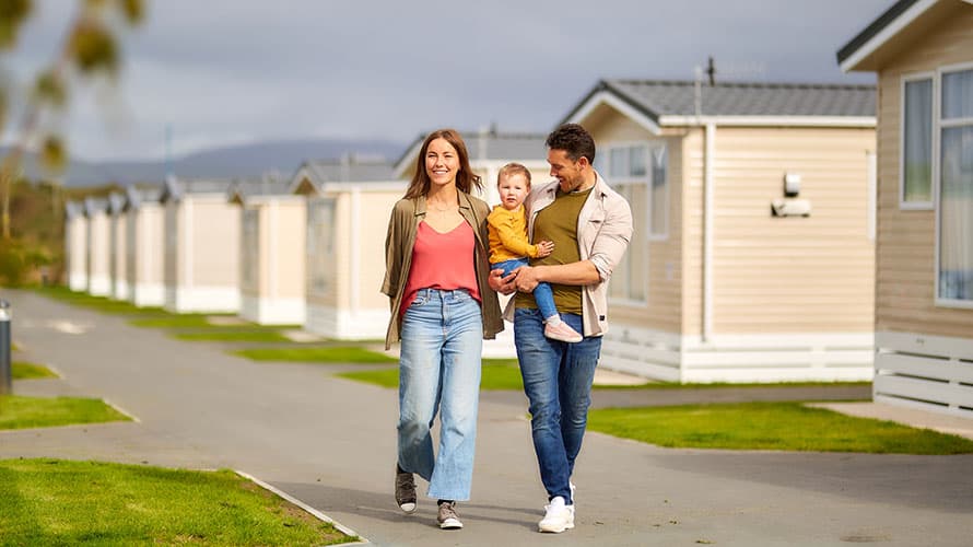 A couple with a toddler walking past a row of caravans