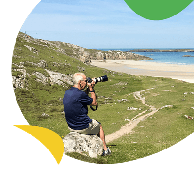 A man photographing a beach with an SLR camera