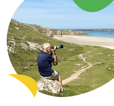 A man photographing a beach with an SLR camera