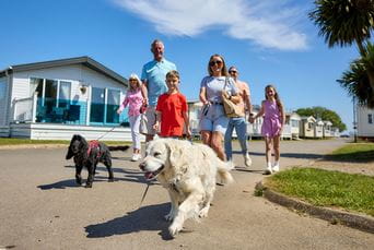 A family with children, dogs and grandparents walking through a holiday park on a summer day
