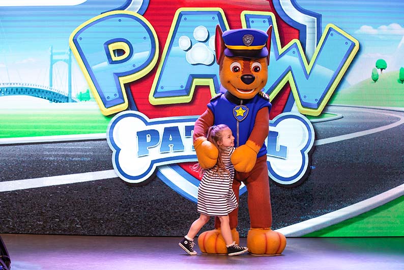 A girl on stage with a character for Paw Patrol