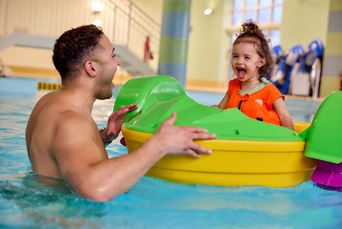 A father in the pool with his daughter using an aquapaddler