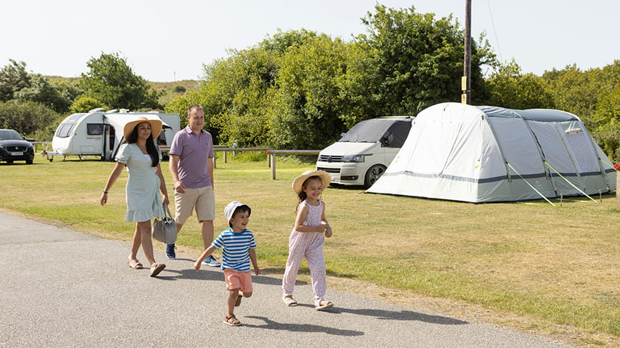 Family walking past a tent at Holywell Bay campsite in Cornwall