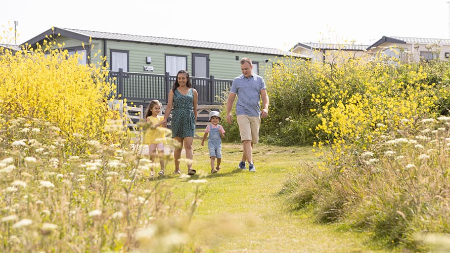 A family walking past a caravan at Crantock Beach in Cornwall