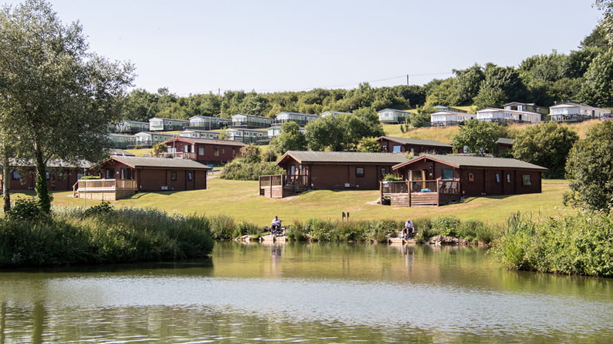 Caravans and lodges overlooking a lake at White Acres in Cornwall