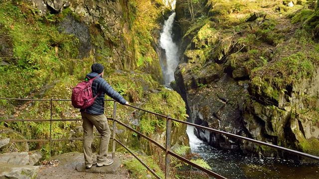 A man standing by a waterfall in the Lake District