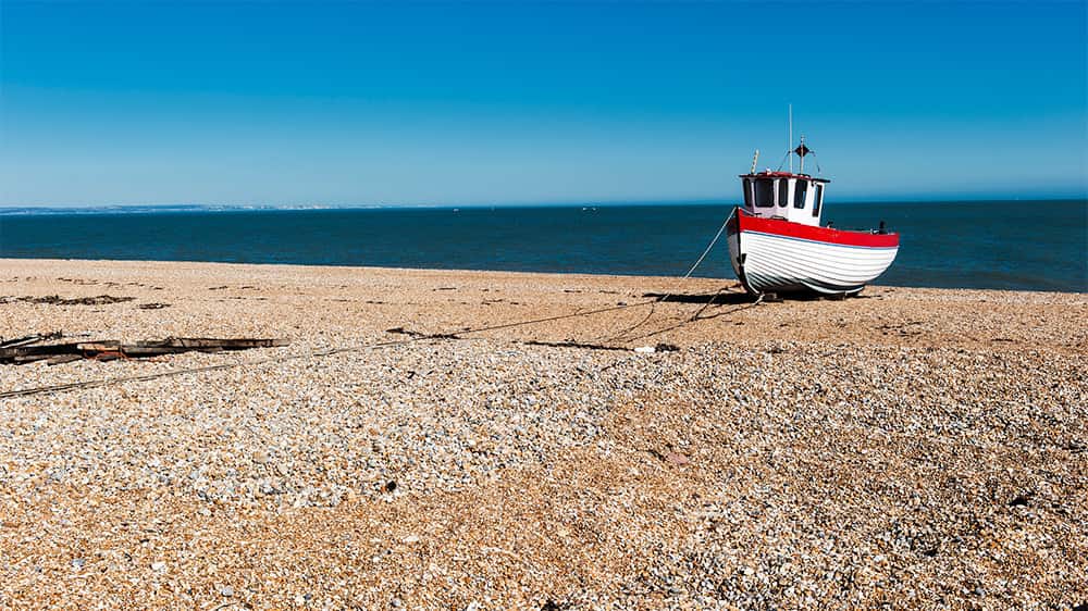 A fishing boat beached on the pebbles at low tide