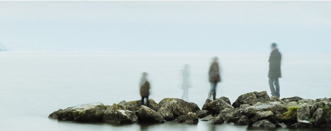 Ghostly figures standing on rocks by the sea