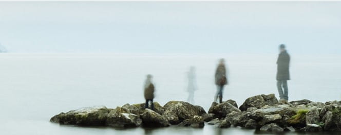 Ghostly figures standing on rocks by the sea