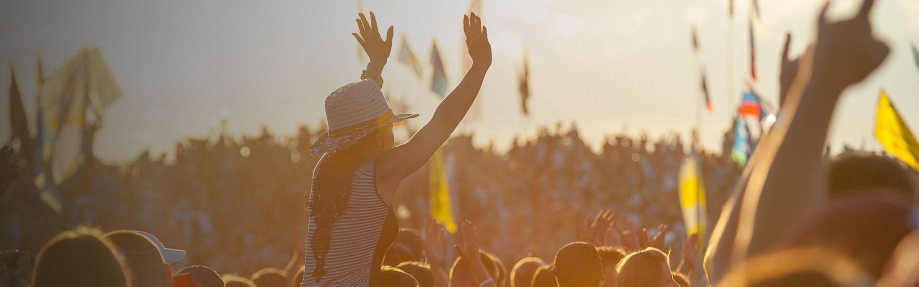 A crowd of concert goers enjoying a festival at sunset
