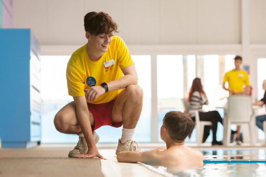 lifeguard accompanying a child in the swimming pool