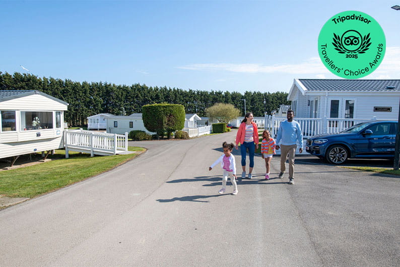 A family walking past a row of caravans at Cayton Bay in Yorkshire