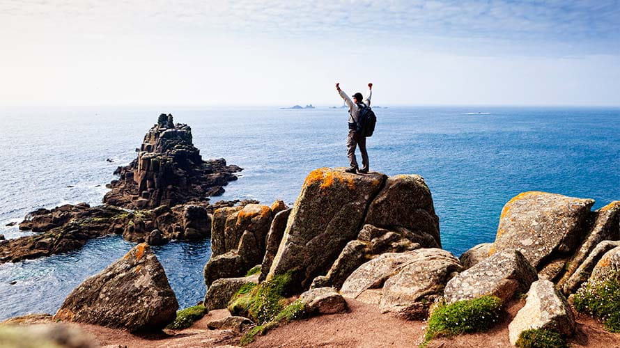 A hiker taking in the view from a coastal lookout in Cornwall