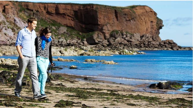 Couple walking along the beach at Eyemouth