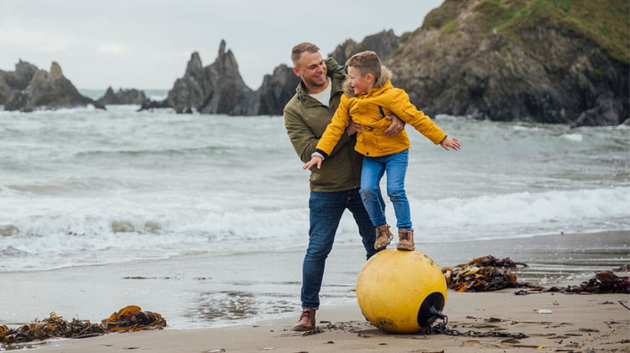 A father and son playing on the beach on a rainy day