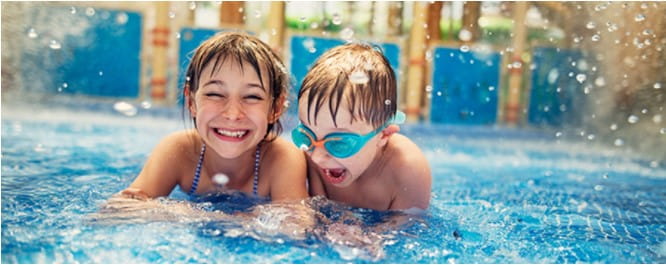 Two kids splashing in an outdoor swimming pool