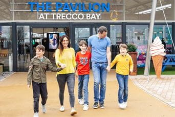 A family walking past the pavilion at Trecco Bay Holiday Park