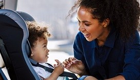 Mother putting her child in a car seat