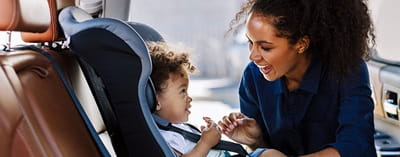 Mother putting her child in a car seat