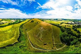 An aerial view of the Cerne Abbas Giant amongst the rolling hills of the Dorset countryside