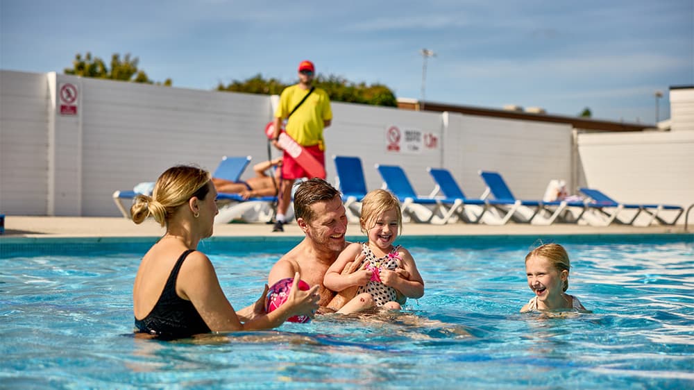 A family playing in the outdoor swimming pool at a Parkdean Resorts holiday park