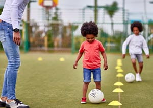 Children kicking footballs around on the sports court