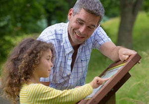 A father and daughter examining an information board on the wildlife nature trail