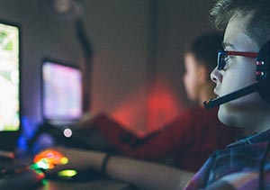 Kids gaming side by side at screens with headsets on