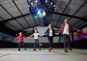 A family skating across the rink at the roller disco