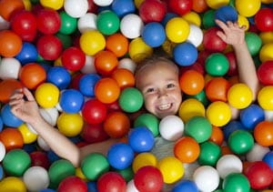 A child lying down in the ball pool of a soft play area