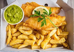 A box of fish and chips with mushy peas