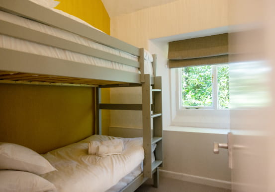 Bunk beds with white sheets and yellow walls