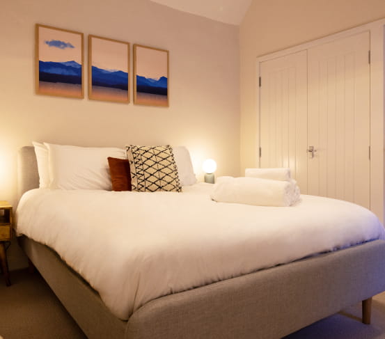Double bed with white bedding and grey headboard
