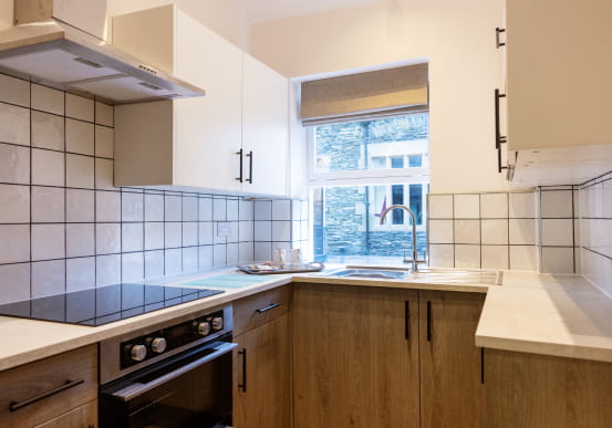 U shaped kitchen with wooden cupboards and white subway tiles