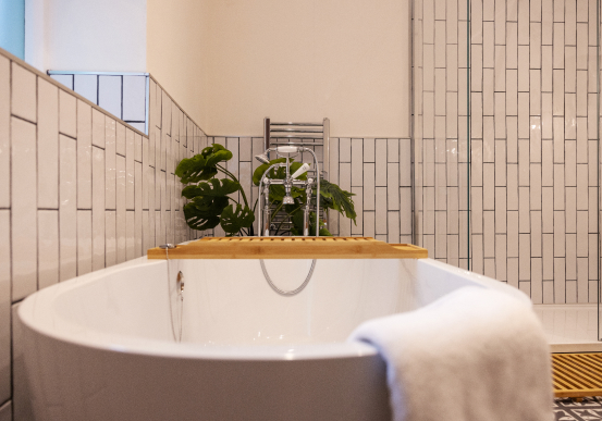 White freestanding bath with wooden tray and plant