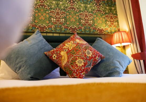 Close up of blue and red patterned cushions on a double bed