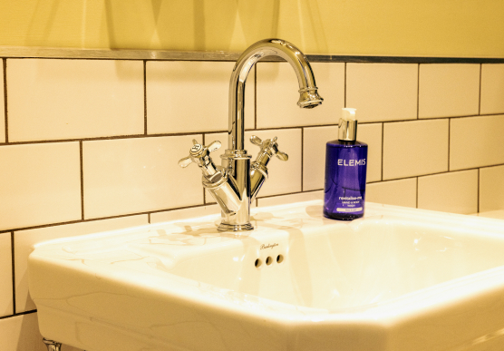 Close up of white sink with silver tap and Elemis hand soap
