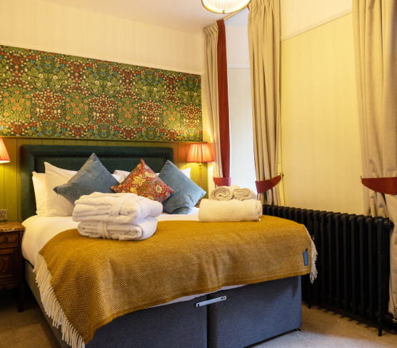 Double bed with blue headboard and mustard throw