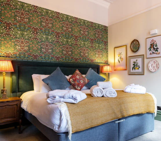 Double bed with navy blue headboard and printed wallpaper