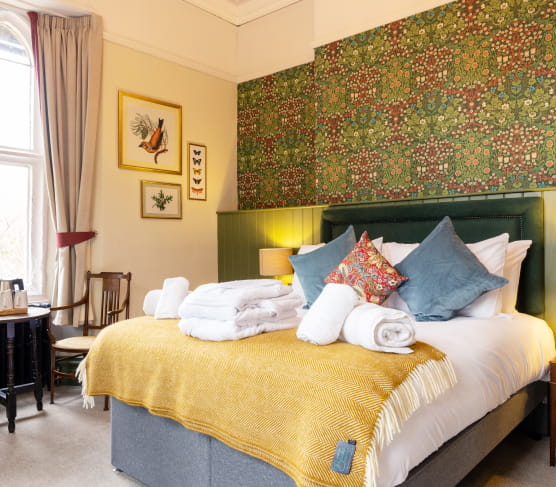 Double bed with navy blue headboard and printed wallpaper