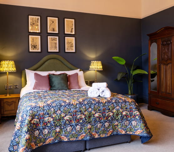 King size bedroom with green headboard and patterned throw