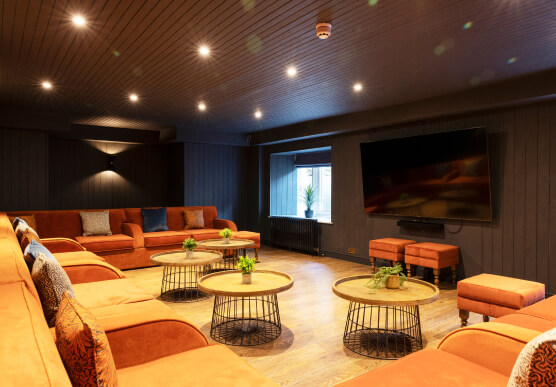 Dark cosy cinema room with orange snuggly corner sofa