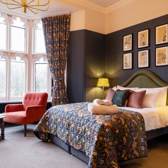 Kingsize bedroom with green headboard and patterned curtains and throw