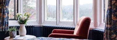 Crushed velvet burnt orange arm chair in the window overlooking Lake Windermere
